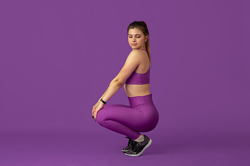 Image showing Beautiful young female athlete practicing on purple studio background, monochrome portrait