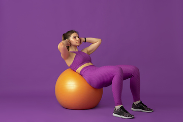 Image showing Beautiful young female athlete practicing on purple studio background, monochrome portrait