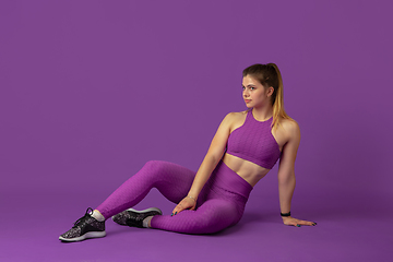 Image showing Beautiful young female athlete practicing on purple studio background, monochrome portrait