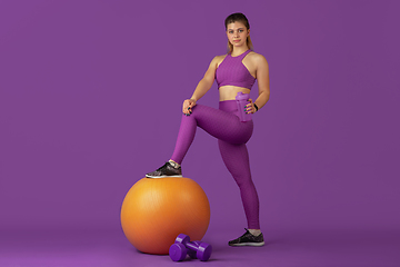 Image showing Beautiful young female athlete practicing on purple studio background, monochrome portrait