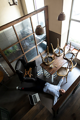 Image showing Public institutions closed due to COVID-19 or Coronavirus outbreak lockdown, stressed owner of small business alone lying down the floor in his cafe, restaurant, bar