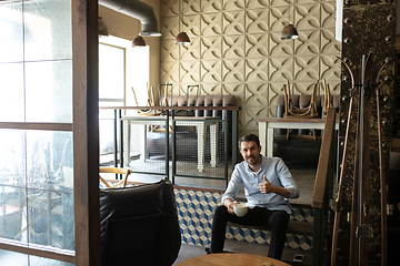 Image showing Small business closed due to COVID-19 or Coronavirus outbreak lockdown, businessman alone in his restaurant, cafe, bar drinking coffee