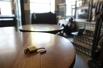 Image showing Public institutions closed due to COVID-19 or Coronavirus outbreak lockdown, stressed owner of small business alone in his cafe, focus on door lock