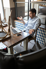 Image showing Public institutions closed due to COVID-19 or Coronavirus outbreak lockdown, stressed owner of small business alone in his cafe, looking for solution