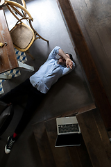 Image showing Public institutions closed due to COVID-19 or Coronavirus outbreak lockdown, stressed owner of small business alone lying down the floor in his cafe, restaurant, bar