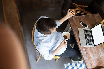 Image showing Public institutions closed due to COVID-19 or Coronavirus outbreak lockdown, stressed owner of small business alone in his cafe, looking for solution, top view