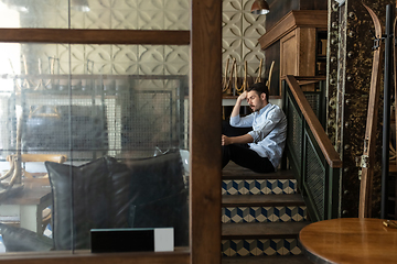 Image showing Public institutions closed due to COVID-19 or Coronavirus outbreak lockdown, stressed owner of small business alone in his cafe, restaurant, bar