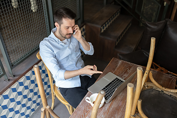 Image showing Public institutions closed due to COVID-19 or Coronavirus outbreak lockdown, stressed owner of small business alone in his cafe, looking for solution