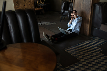 Image showing Public institutions closed due to COVID-19 or Coronavirus outbreak lockdown, stressed owner of small business alone in his cafe, despair lying down the floor