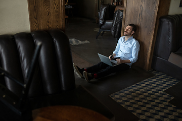 Image showing Public institutions closed due to COVID-19 or Coronavirus outbreak lockdown, stressed owner of small business alone in his cafe, despair lying down the floor