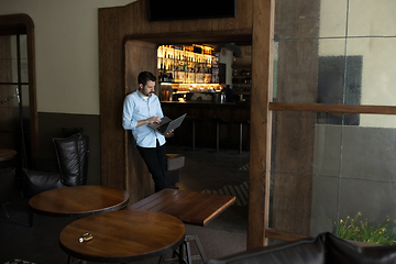 Image showing Public institutions closed due to COVID-19 or Coronavirus outbreak lockdown, stressed owner of small business alone in his cafe, looking for solution