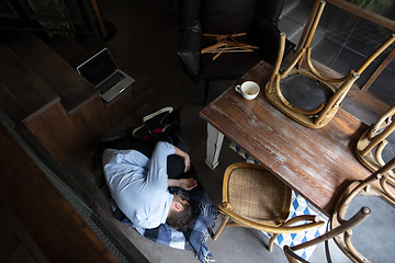 Image showing Public institutions closed due to COVID-19 or Coronavirus outbreak lockdown, stressed owner of small business alone lying down the floor in his cafe, restaurant, bar