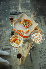 Image showing Leftover pizza and popcorn on the table after family spending time together, watching cinema