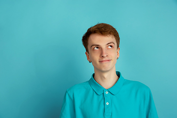 Image showing Caucasian young man\'s monochrome portrait on blue studio background, emotinal and beautiful