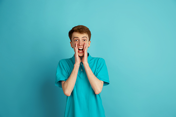 Image showing Caucasian young man\'s monochrome portrait on blue studio background, emotinal and beautiful