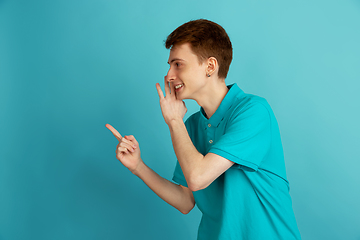 Image showing Caucasian young man\'s monochrome portrait on blue studio background, emotinal and beautiful