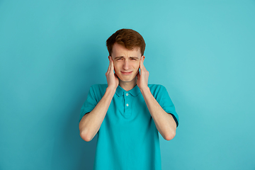 Image showing Caucasian young man\'s monochrome portrait on blue studio background, emotinal and beautiful