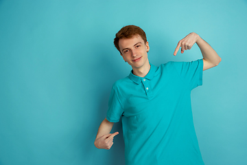 Image showing Caucasian young man\'s monochrome portrait on blue studio background, emotinal and beautiful