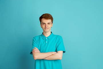 Image showing Caucasian young man\'s monochrome portrait on blue studio background, emotinal and beautiful