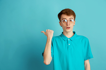 Image showing Caucasian young man\'s monochrome portrait on blue studio background, emotinal and beautiful