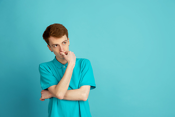 Image showing Caucasian young man\'s monochrome portrait on blue studio background, emotinal and beautiful