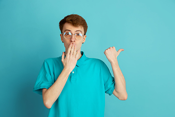 Image showing Caucasian young man\'s monochrome portrait on blue studio background, emotinal and beautiful