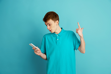 Image showing Caucasian young man\'s monochrome portrait on blue studio background, emotinal and beautiful