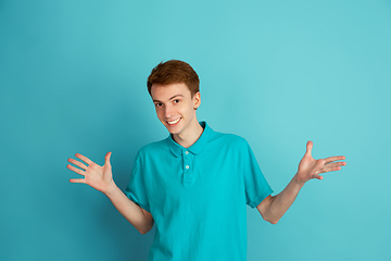 Image showing Caucasian young man\'s monochrome portrait on blue studio background, emotinal and beautiful