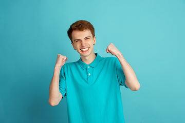 Image showing Caucasian young man\'s monochrome portrait on blue studio background, emotinal and beautiful