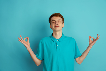 Image showing Caucasian young man\'s monochrome portrait on blue studio background, emotinal and beautiful