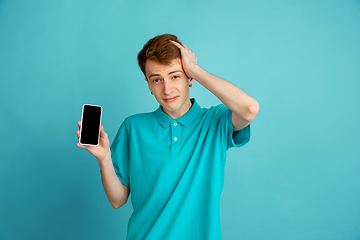 Image showing Caucasian young man\'s monochrome portrait on blue studio background, emotinal and beautiful