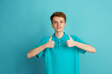 Image showing Caucasian young man\'s monochrome portrait on blue studio background, emotinal and beautiful