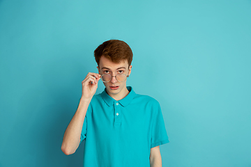 Image showing Caucasian young man\'s monochrome portrait on blue studio background, emotinal and beautiful