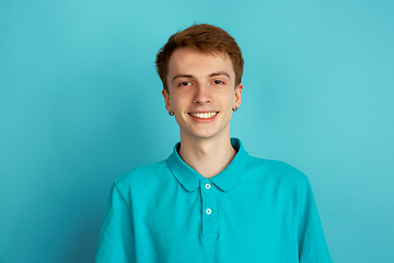 Image showing Caucasian young man\'s monochrome portrait on blue studio background, emotinal and beautiful