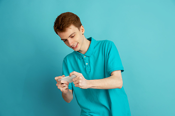 Image showing Caucasian young man\'s monochrome portrait on blue studio background, emotinal and beautiful