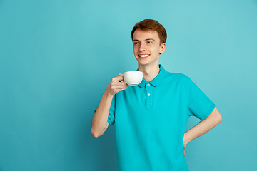 Image showing Caucasian young man\'s monochrome portrait on blue studio background, emotinal and beautiful