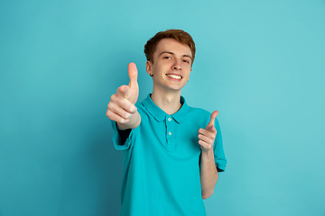 Image showing Caucasian young man\'s monochrome portrait on blue studio background, emotinal and beautiful