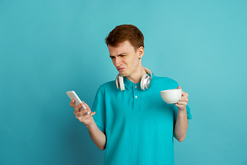 Image showing Caucasian young man\'s monochrome portrait on blue studio background, emotinal and beautiful