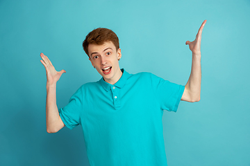 Image showing Caucasian young man\'s monochrome portrait on blue studio background, emotinal and beautiful