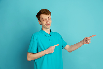 Image showing Caucasian young man\'s monochrome portrait on blue studio background, emotinal and beautiful