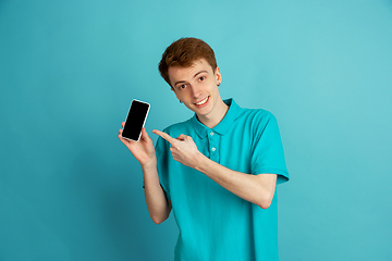 Image showing Caucasian young man\'s monochrome portrait on blue studio background, emotinal and beautiful