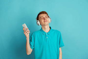 Image showing Caucasian young man\'s monochrome portrait on blue studio background, emotinal and beautiful