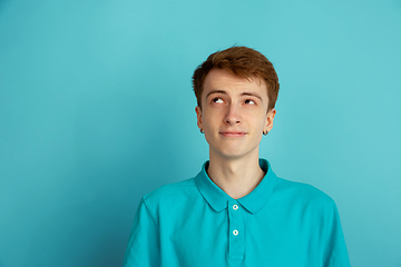 Image showing Caucasian young man\'s monochrome portrait on blue studio background, emotinal and beautiful