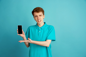 Image showing Caucasian young man\'s monochrome portrait on blue studio background, emotinal and beautiful