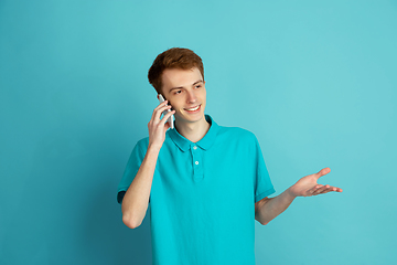 Image showing Caucasian young man\'s monochrome portrait on blue studio background, emotinal and beautiful