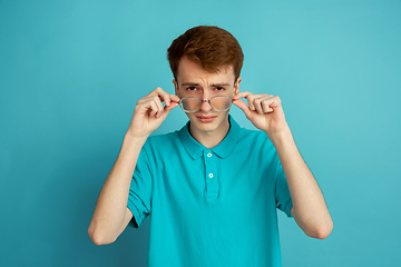 Image showing Caucasian young man\'s monochrome portrait on blue studio background, emotinal and beautiful