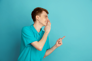 Image showing Caucasian young man\'s monochrome portrait on blue studio background, emotinal and beautiful