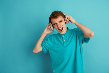 Image showing Caucasian young man\'s monochrome portrait on blue studio background, emotinal and beautiful