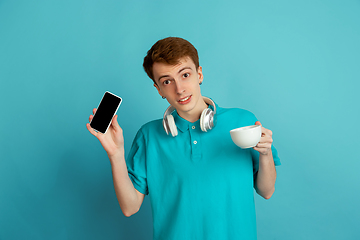 Image showing Caucasian young man\'s monochrome portrait on blue studio background, emotinal and beautiful