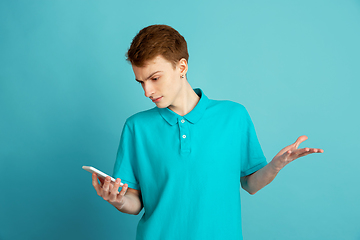 Image showing Caucasian young man\'s monochrome portrait on blue studio background, emotinal and beautiful